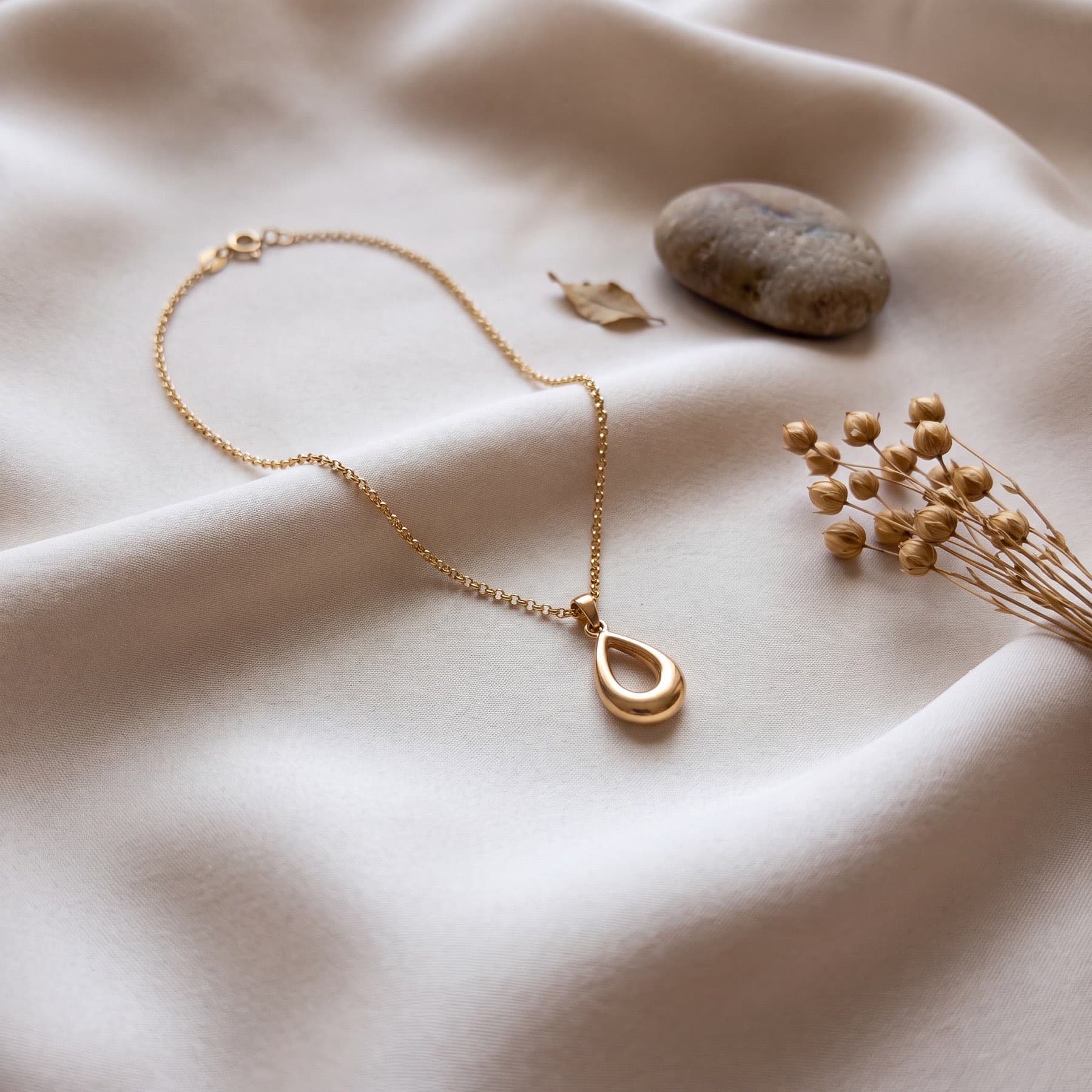 A necklace shot on a table with a phone, and the same piece as a clean product shot